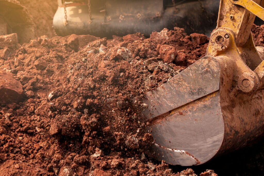 Closeup bucket of backhoe digging the soil at construction site. Crawler excavator digging on demoli